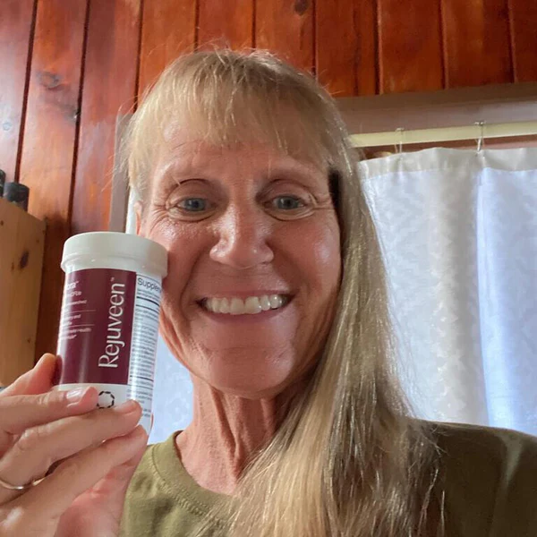 Person smiling and holding a bottle labeled 'Cosara' in a wooden room.