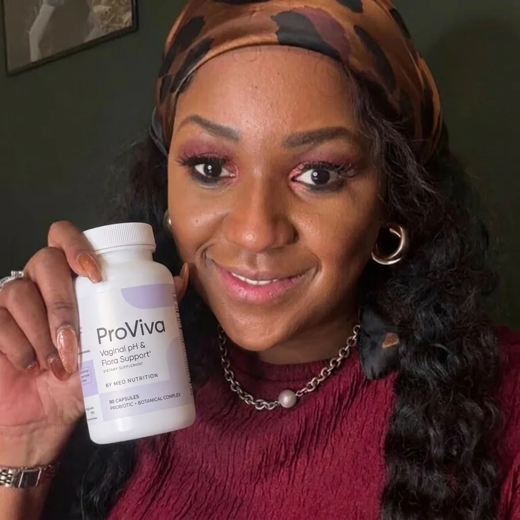 Person holding a bottle, smiling, wearing a headscarf and maroon top.